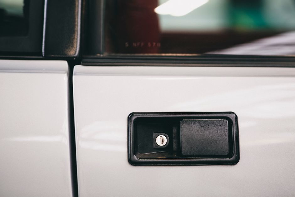 Detailed close-up of a vintage car door handle with lock mechanism.