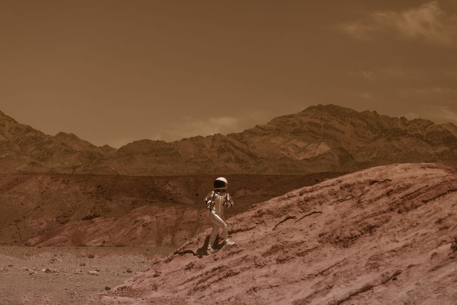 Astronaut walking on a barren landscape resembling Mars, with futuristic and adventurous vibes.