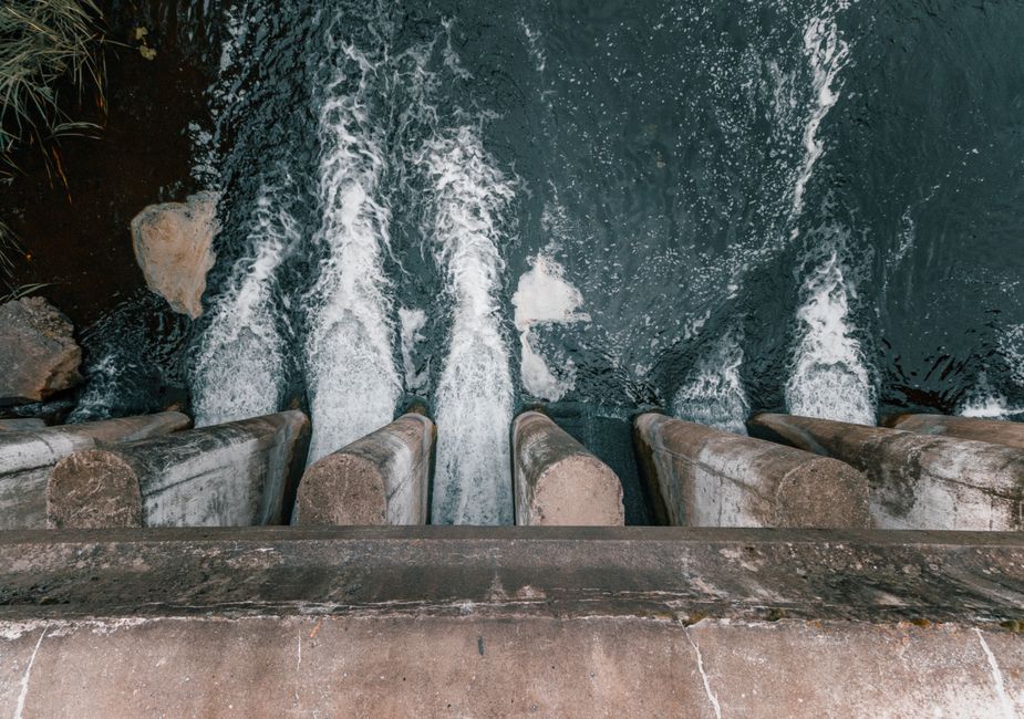 Aerial view of cascading water over a concrete dam showcasing turbulent flow and water management.