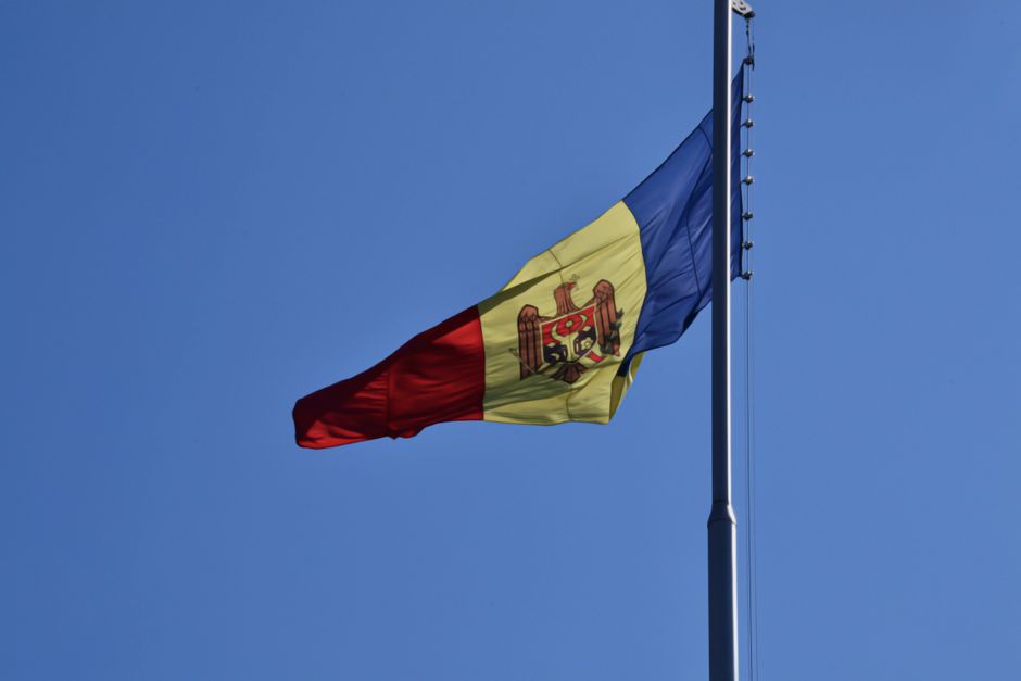 The Moldovan flag elegantly flutters on a flagpole under a clear blue sky.