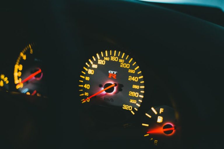Close-up view of a car's illuminated dashboard and speedometer with glowing lights.