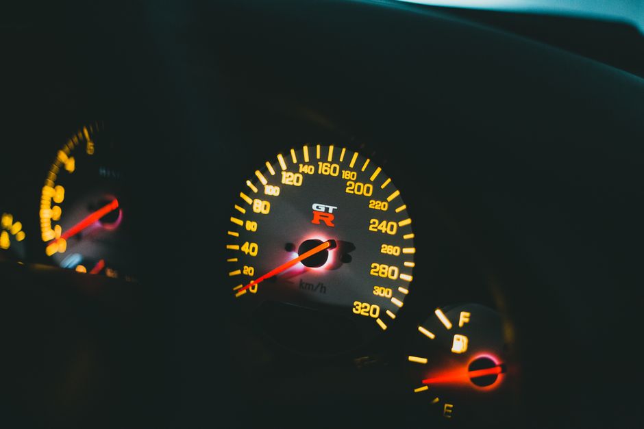 Close-up view of a car's illuminated dashboard and speedometer with glowing lights.
