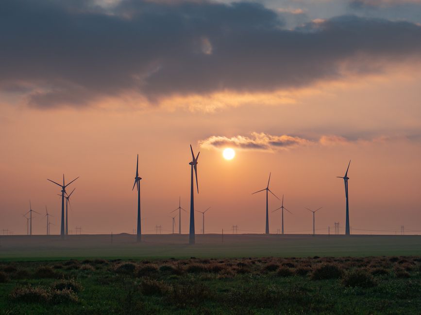 A serene landscape of wind turbines in Romania during sunset, symbolizing renewable energy and sustainability.