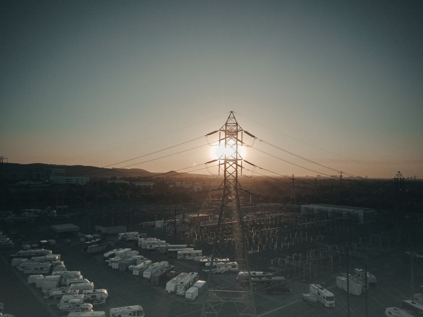 Aerial view of a high voltage tower and energy park during sunset, symbolizing renewable energy.
