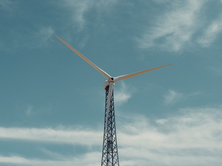 A towering wind turbine stands tall, harnessing wind energy under a clear blue sky.