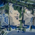 Aerial view of suburban houses featuring solar panels and green lawns, symbolizing eco-friendly living.