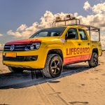 A vibrant yellow lifeguard vehicle parked on a sunny beach, ensuring safety for beachgoers.