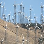 A large wind farm with numerous turbines on a sunlit hillside, promoting renewable energy.
