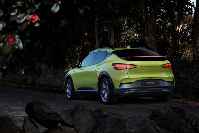 Capture of a luxury Genesis GV60 electric car parked on a winding road surrounded by nature.