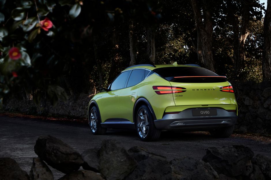 Capture of a luxury Genesis GV60 electric car parked on a winding road surrounded by nature.