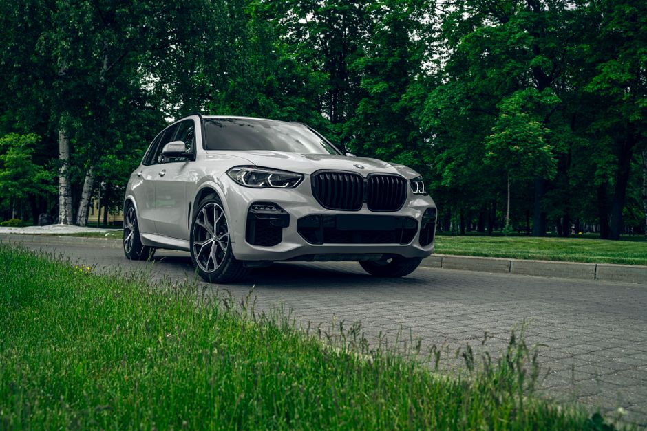 White BMW X5 SUV parked on a scenic road surrounded by lush greenery, showcasing elegance and style.