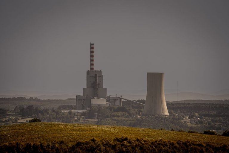 Distant view of a power plant with cooling towers amidst a vast landscape, illustrating energy production.