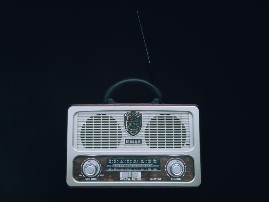Classic vintage radio with antenna on black background, showcasing its retro design.