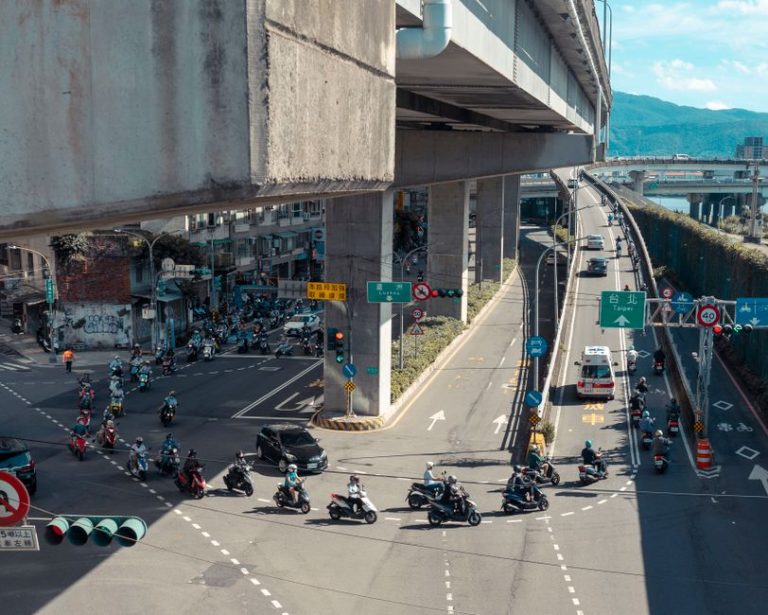 Vibrant urban scene in Taipei showcasing busy traffic under an elevated expressway with visible signage.