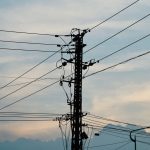 Silhouette of power lines and pole against a vibrant sunset sky.