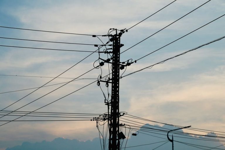 Silhouette of power lines and pole against a vibrant sunset sky.