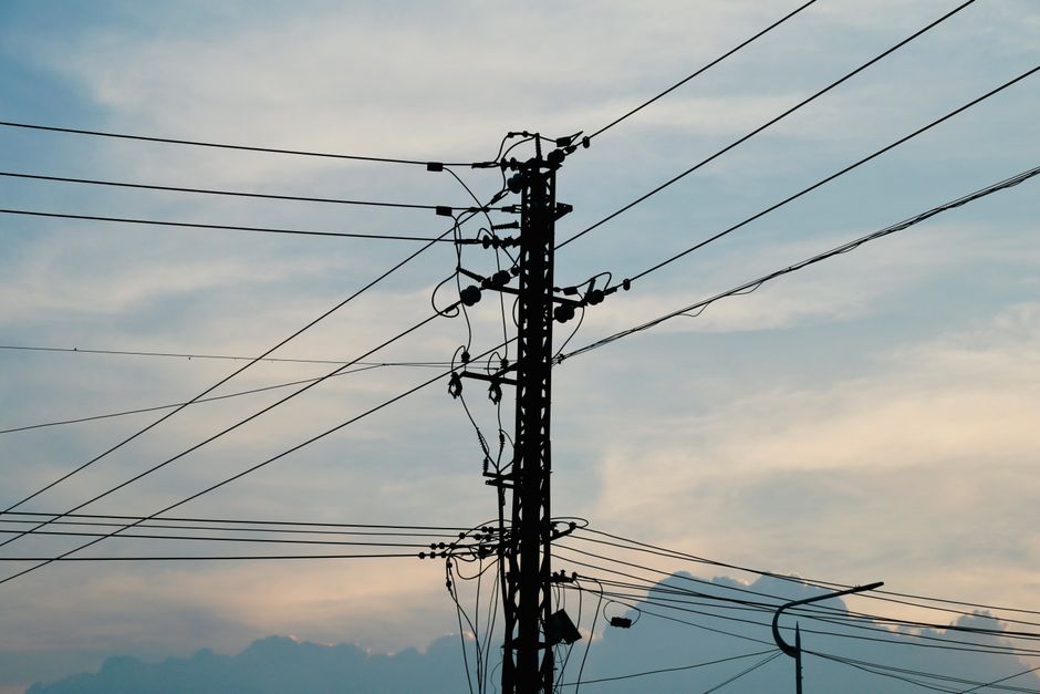 Silhouette of power lines and pole against a vibrant sunset sky.