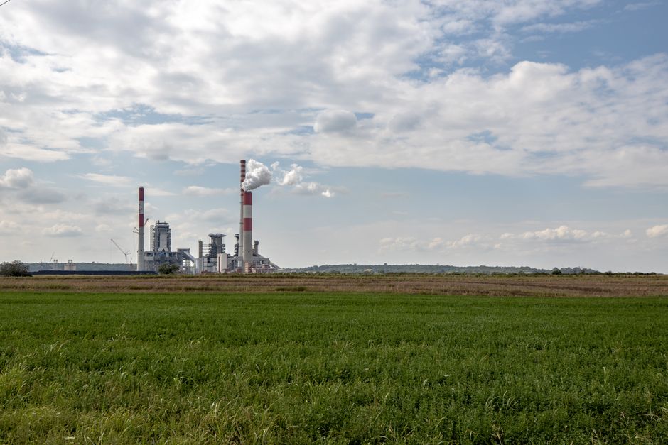 Thermal power plant with smokestacks emitting in Serbia's rural landscape.