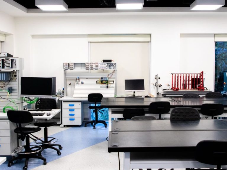 Bright and well-equipped modern technology lab featuring computers, workstations, and desks.