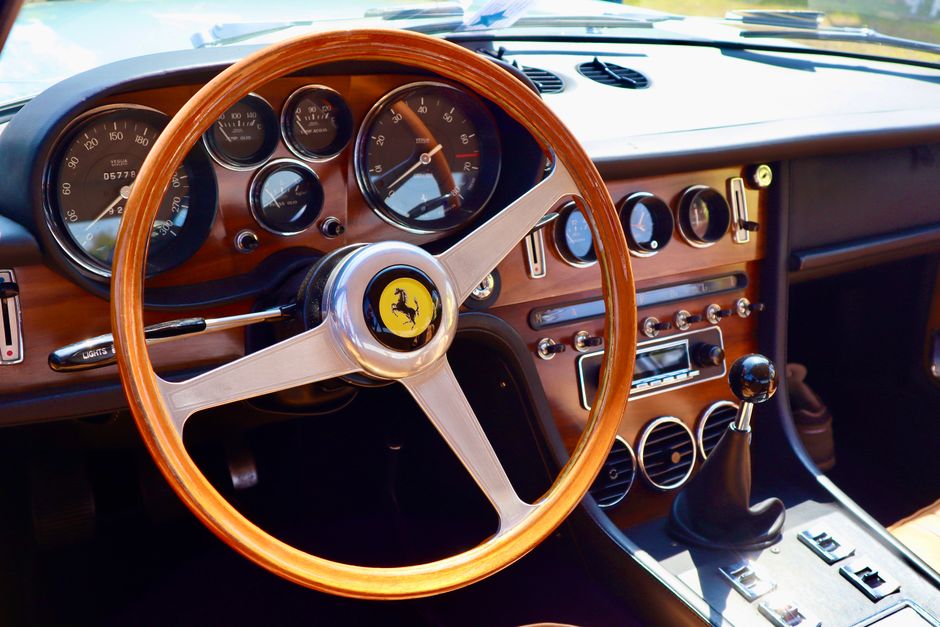 Interior view of a classic Ferrari featuring a vintage wooden steering wheel and dashboard.