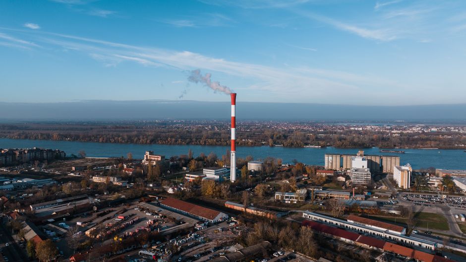 A stunning aerial view of a Belgrade industrial area with a prominent smokestack and river.