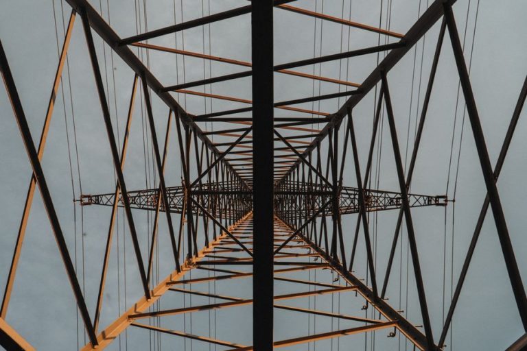 Looking up through a lattice structure of a towering metal construction against the sky.
