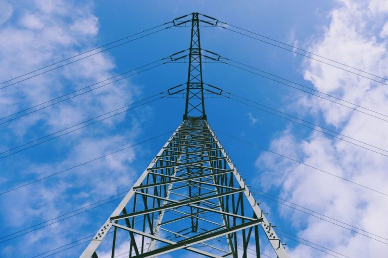 Low angle view of a tall transmission tower against a clear blue sky with clouds in Hanau, Germany.