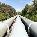 Large industrial pipeline traversing through a green forest in Geesthacht, Germany.