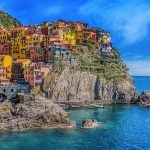Vivid view of Manarola's colorful houses perched on cliffs, overlooking the blue sea.