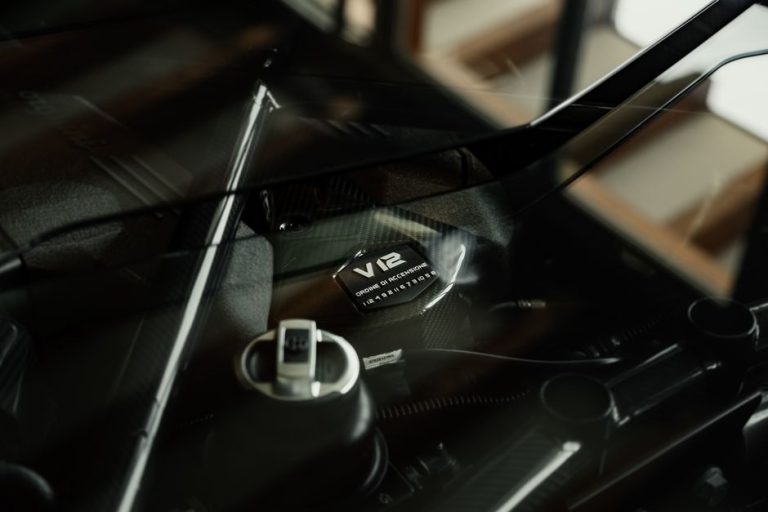 Detailed view of a V12 engine part under a reflective glass cover, showcasing engineering design.