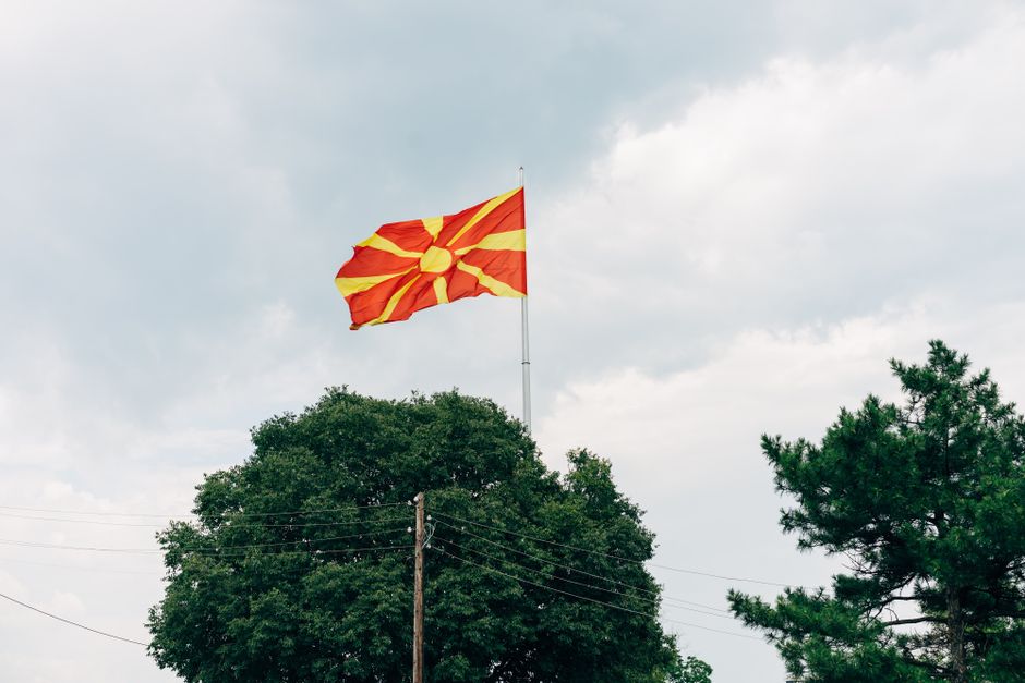 The national flag of North Macedonia waves prominently against an overcast sky.