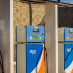 Three blue OLA Energy gas pumps at an outdoor station on a sunny day.