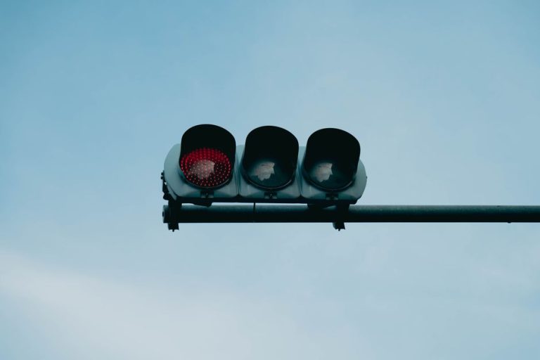 A close-up of a red traffic light set against a clear blue sky, conveying safety and caution.