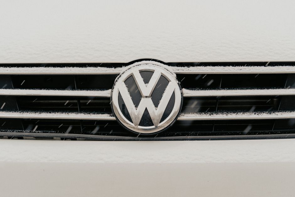 Closeup of a snow-dusted Volkswagen car grille shows the iconic VW logo.