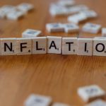 Scrabble letter tiles spelling 'INFLATION' on a wooden table, signifying economic concepts.