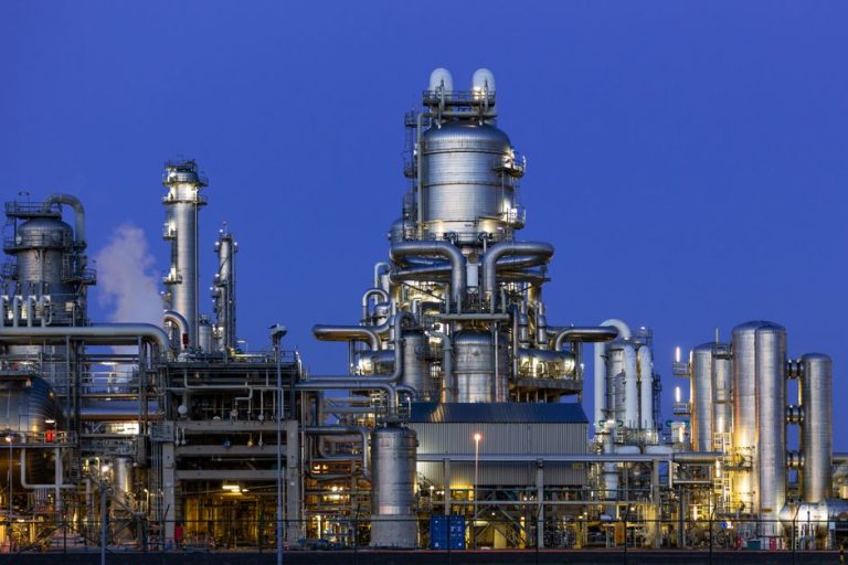 A modern industrial refinery structure under a clear twilight sky in Zuid-Holland, Netherlands.