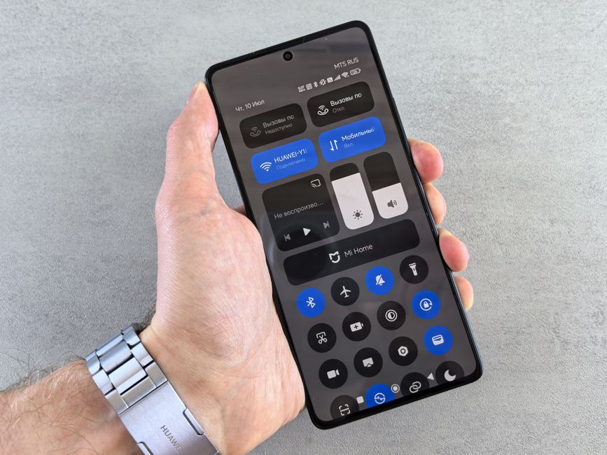 Close-up of a hand holding a smartphone displaying its control panel interface.
