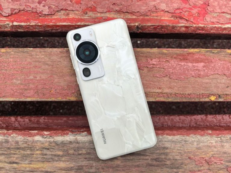 Modern smartphone with a textured back cover lies on a rustic wooden bench outdoors.