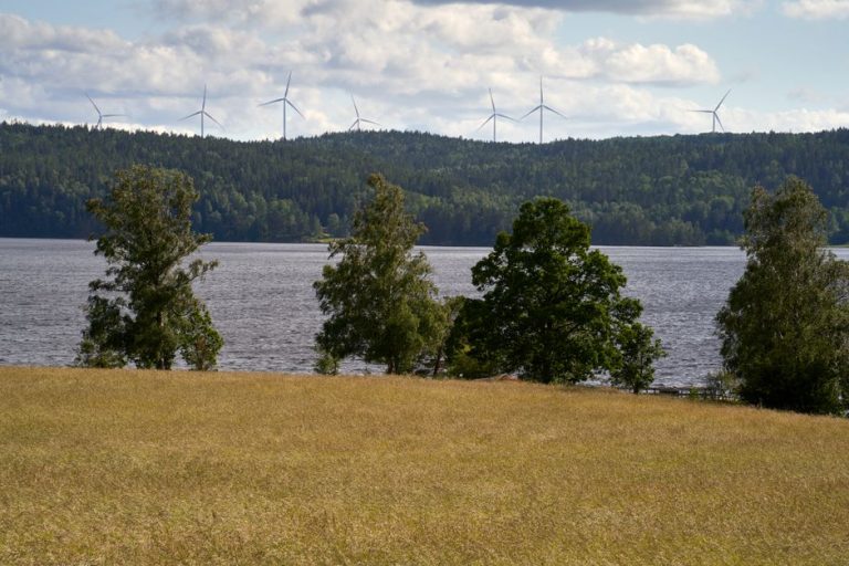 Idyllic Swedish landscape with wind turbines and lush greenery by a lake in Håverud, Västra Götaland.