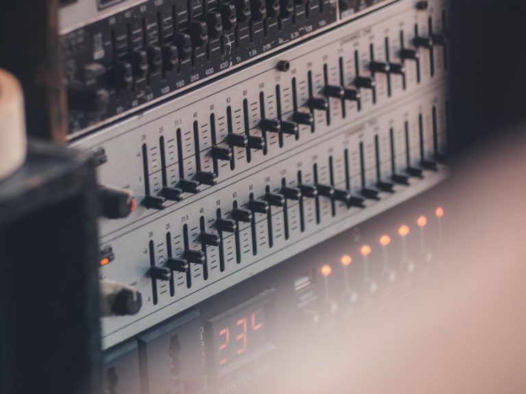 Detailed view of audio equalizer equipment in a professional studio setup, showcasing faders and controls.