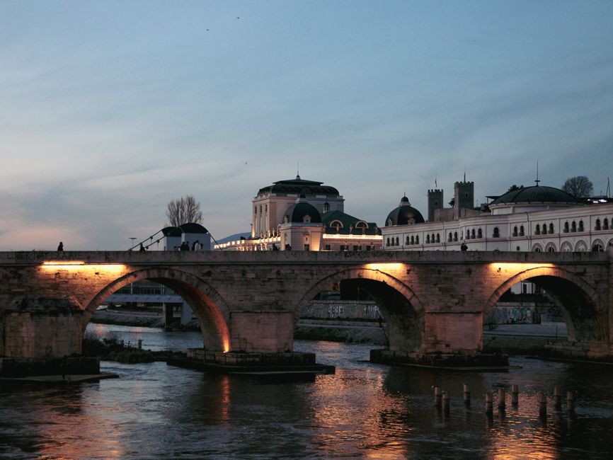 Evening shot of Stone Bridge over Vardar River in Skopje, illuminated by lights.
