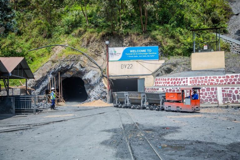Mining entrance with tunnel BV22, rail cars, and workers in safety gear at Trinity site.