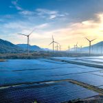 Stunning landscape featuring solar panels and wind turbines at sunrise, symbolizing sustainable energy.