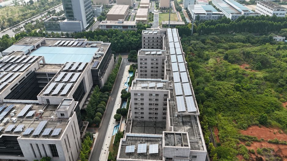 Aerial urban landscape with solar-panel rooftops and green spaces.