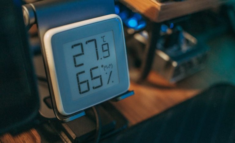 Close-up of a digital hygrometer showing temperature and humidity indoors.