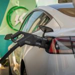 Close-up of Tesla Model 3 connected to a charging station, highlighting eco-friendly transportation.