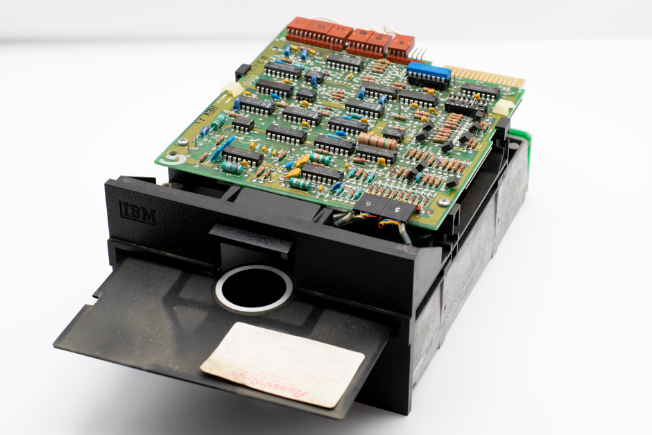 Close-up view of a vintage IBM circuit board and disk drive showcasing retro computer technology.