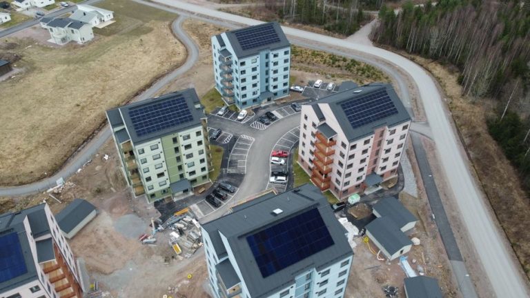 Aerial view of eco-friendly apartments with solar panels in a rural area.