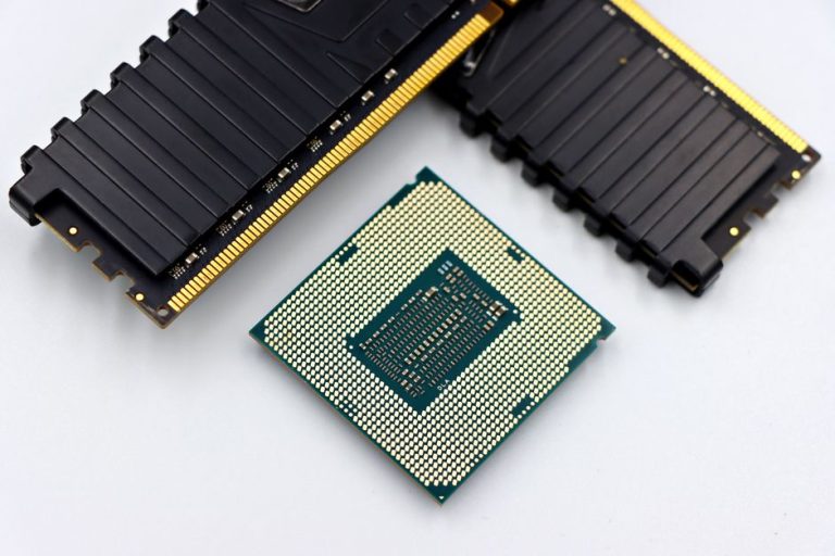 A CPU and RAM sticks displayed on a white surface, showcasing computer hardware components.