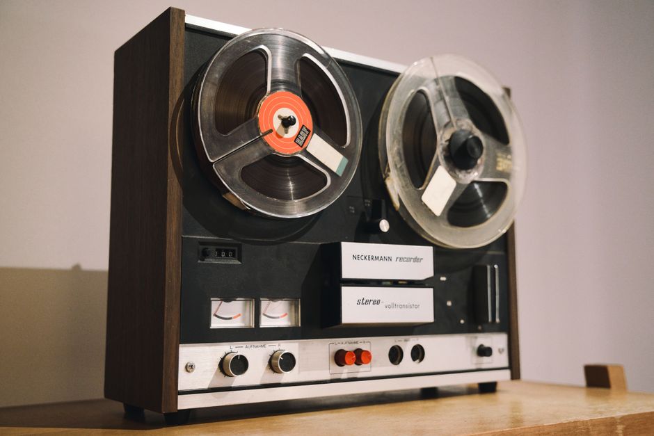 Close-up of a classic reel-to-reel tape recorder on a wooden surface, showcasing audio nostalgia.
